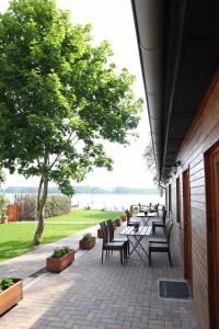 eine Terrasse mit Tischen, Stühlen und einem Baum in der Unterkunft Seeblick Apartment am Mellensee in Mellensee