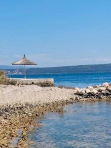 a beach with an umbrella and the water at Apartments Possedaria in Posedarje