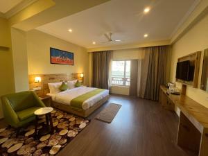 um quarto de hotel com uma cama e uma cadeira verde em Crown Himalaya em Leh