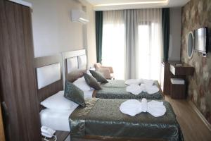 two beds in a hotel room with towels on them at Inciler Hotel in Altınoluk +35 photos