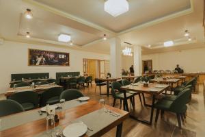 a restaurant with wooden tables and green chairs at Crown Himalaya in Leh