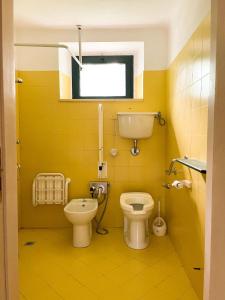 a yellow bathroom with a toilet and a window at Casale Al Fiume in Grottazzolina
