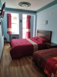 - une chambre avec 2 lits avec des draps rouges et une fenêtre dans l'établissement Uyuni HOSTAL YOKOSO, à Uyuni