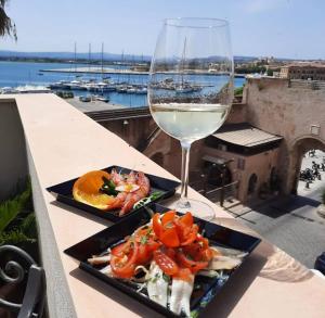 シラクーサにあるB&B Marina di Ortigiaのテーブルの上に2皿の料理とワイン1杯