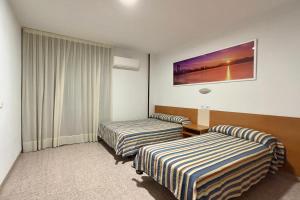 a hotel room with two beds and a window at Pensión La Orozca Benidorm in Benidorm