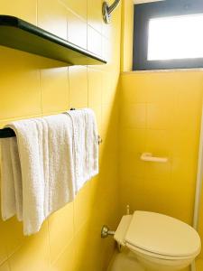 a yellow bathroom with a toilet and towels at Casale Al Fiume in Grottazzolina