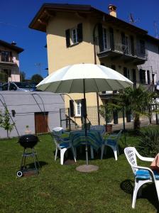 un tavolo e sedie sotto un ombrellone in un cortile di Casa Lidia a Ossuccio
