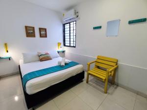 a bedroom with a bed and a yellow chair at Bona Vida Apartments in Ríohacha