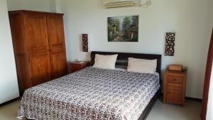 a bedroom with a bed and a wooden cabinet at Villa Saraswati Meras in Wori