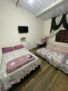 a bedroom with two beds and a flat screen tv at Recanto do Paraiso in Peruíbe