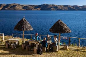 a group of people sitting at a table near the water at Waynapicchu Lodge Isla de la Luna Bolivia in Isla de la Luna