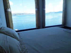 a bedroom with a large window looking out at the water at Waynapicchu Lodge Isla de la Luna Bolivia in Isla de la Luna