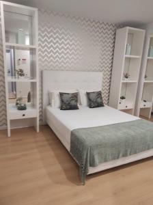 - une chambre avec un lit blanc et des étagères blanches dans l'établissement By the Sea, à Nazaré