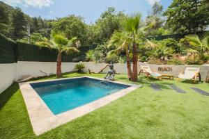 a swimming pool in a yard with grass and palm trees at Ô Balinais mini villa avec spa et piscine chauffée privative Marseille in Marseille