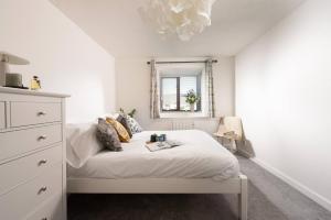 um quarto branco com uma cama e um espelho em Quiet family-friendly apartment 250 metres from beach and town em Newquay