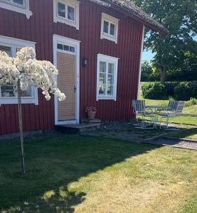 ein rotes Haus mit einem Tisch und Stühlen davor in der Unterkunft Uddebogård 2 in Hjo