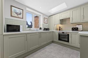 a large kitchen with white cabinets and a window at 119 Flat 2 Northgate st - Stylish one bedroom apartment set within walking distance to town, spacious living space with public car park close by in Bury Saint Edmunds +8 photos