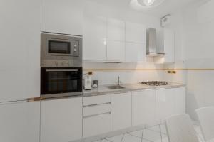 una cucina bianca con forno a microonde e lavandino di Angela Suite a Portoferraio