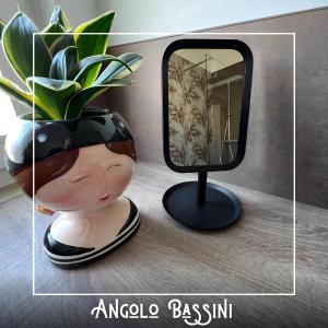 ein Spiegel auf einem Stand neben einer Vase mit einer Pflanze in der Unterkunft Angolo Bassini - Apartment in Verona