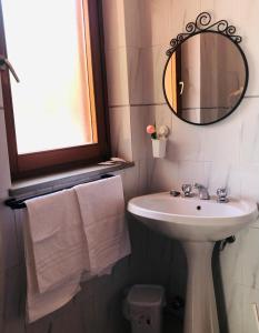 ein Badezimmer mit einem Waschbecken, einem Spiegel und Handtüchern in der Unterkunft Villaggio Residence Chalet degli Ulivi in Marina di Camerota