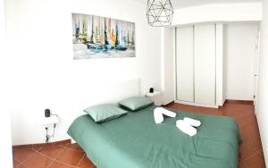 ein Schlafzimmer mit einem grünen Bett und weißen Handtüchern darauf in der Unterkunft Casas da Cacilda II in Nazaré
