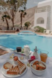 a table with a breakfast of eggs and toast next to a pool at Sfiga villas in Perissa