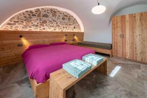 - une chambre avec un lit doté de draps violets et d'un banc dans l'établissement Albertini Vacanze, à Brez