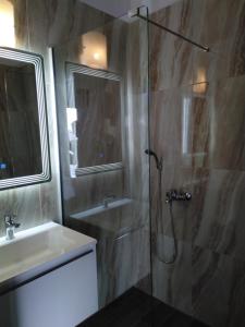 ein Bad mit einer Glasdusche und einem Waschbecken in der Unterkunft Studios Spiros Parga in Parga