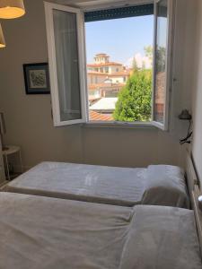 Leonardo luxury apartment في فلورنسا: غرفة نوم بسريرين ونافذة مطلة