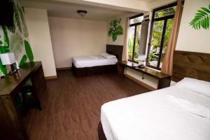 a hotel room with two beds and two windows at Hotel Ariana in San Pedro La Laguna