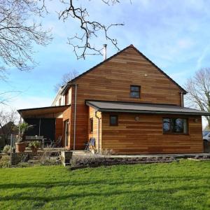 a large wooden house in a yard with green grass at Hide on the Hill Cottage in Wells