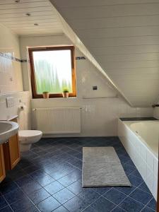 a bathroom with a tub and a toilet and a window at Landhaus mit Pool in Burgthann