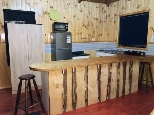 a kitchen with wooden walls and a counter with stools at Cabaña Punta Nao 2 - Carretera Austral in Hualaihué