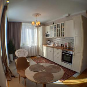 eine Küche mit weißen Schränken sowie einem Tisch und Stühlen in der Unterkunft Apartament Prowansalski in Danzig