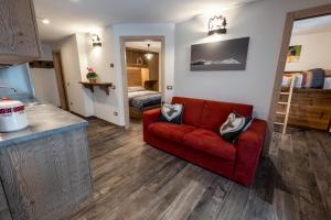 a living room with a red couch and a bedroom at Casa Marzari Lavarone - Appartamento Ginepro in Chiesa +8 photos