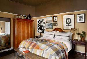 1 dormitorio con 1 cama y algunas fotos en la pared en Mukti, en Nieu-Bethesda
