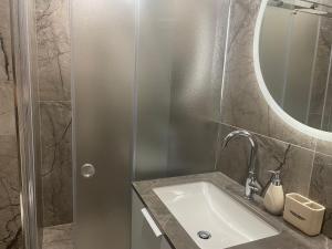 a bathroom with a sink and a shower with a mirror at Oškinio Apartamentai in Palanga +9 photos