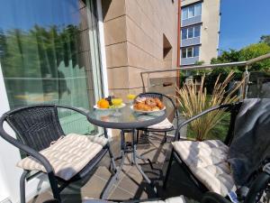 a table with a plate of food on a balcony at Oškinio Apartamentai in Palanga