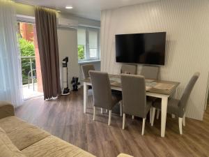 a dining room with a table and chairs and a television at Oškinio Apartamentai in Palanga