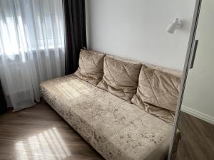 a couch sitting in the corner of a room at Oškinio Apartamentai in Palanga