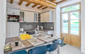 een keuken met een wastafel en een aanrecht met blauwe stoelen bij 3 Bedroom Nice Home In Fierville-les-mines in Fierville-les-Mines