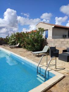 - une piscine avec 2 chaises longues à côté d'une maison dans l'établissement les olivades, à Magalas