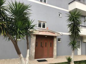 a house with a brown door and two palm trees at Vila 3 in Himare