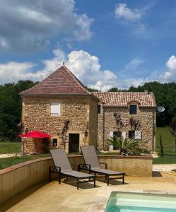 a house with two chairs next to a swimming pool at Le Bos Dordogne in Soulaures