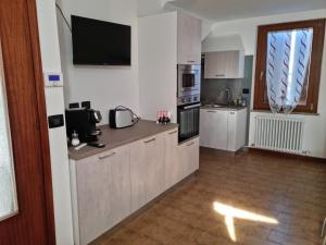 a kitchen with white cabinets and a television on the wall at DA ARTU' in Udine