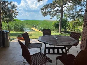 a table and chairs on a patio with a view at Casa di Bianca - közvetlen vízparti nyaraló in Siófok