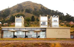 a building with umbrellas in front of a mountain at Hotel Onkel Inn Torres de Copacabana in Copacabana