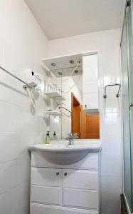 a white bathroom with a sink and a mirror at Apartman Leona in Rakovica