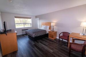 a bedroom with a bed and a desk and a television at Borden Inn and Suites in Angus