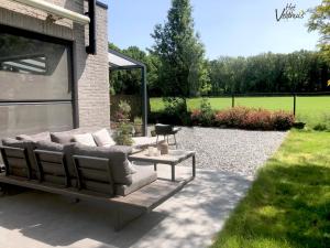 a patio with a couch and a table at Het Veldhuis in As